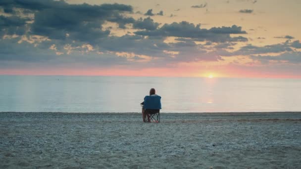 Full shot of woman admiring sunset on the sea sitting in folding tourist chair — Stock Video