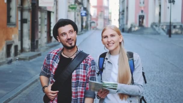 Feliz joven pareja turística con mapa caminando y mirando la arquitectura de la ciudad vieja — Vídeos de Stock