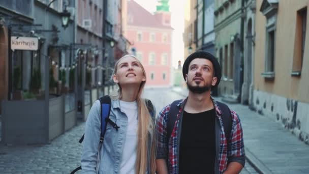 Casal feliz de turistas com mapa andando na rua central da antiga cidade europeia — Vídeo de Stock