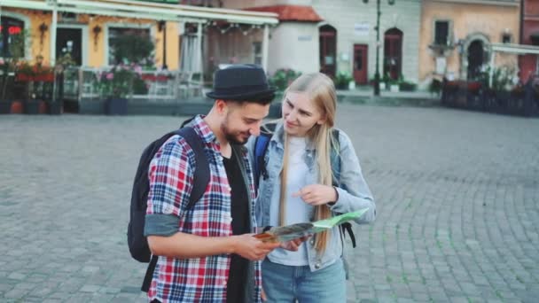 Fiatal turisták pár megtalálja a szükséges úti cél térképen és csodálattal környéke — Stock videók