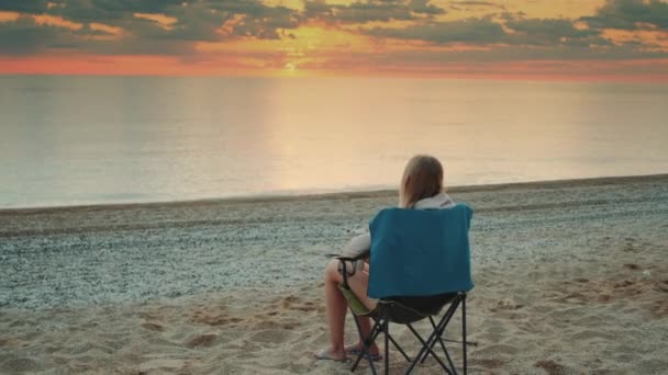 Woman sitting on camping chair and drinking coffee — Stock Video