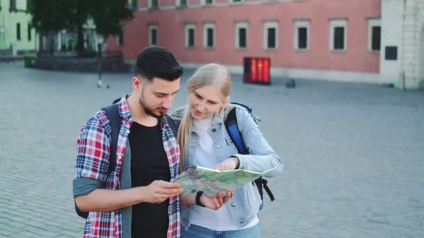 Férfi és női turisták térképpel, akik új történelmi helyet keresnek a városközpontban — Stock videók