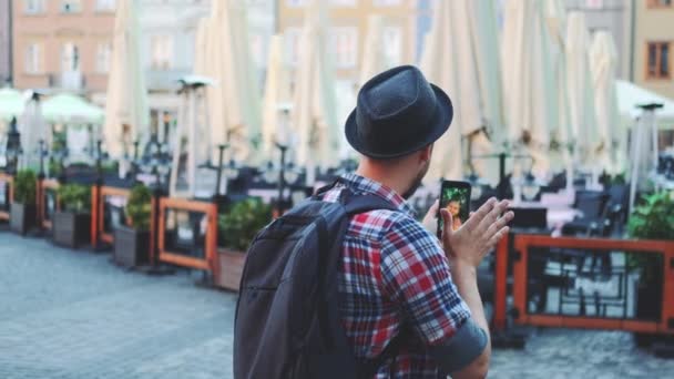 Vista trasera de turista haciendo videollamada en smartphone con turista femenina de otro lugar — Vídeos de Stock