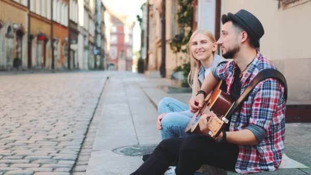 Туристы сидят на тротуаре, играют на гитаре и отдыхают — стоковое видео
