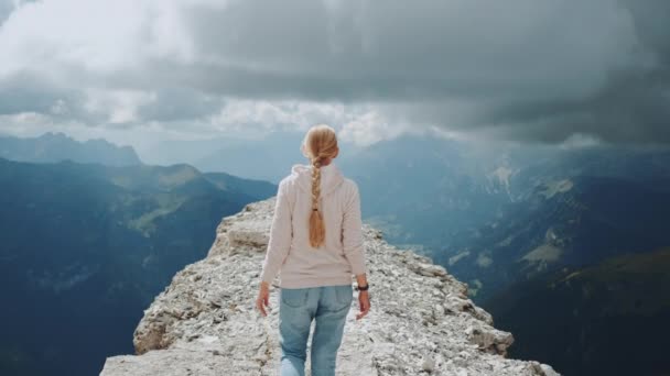 Visão traseira da mulher loira andando no topo da montanha sob as nuvens — Vídeo de Stock
