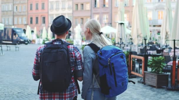 Vista de la pareja de turistas con bolsas chequeando mapa en la plaza central de la ciudad — Vídeos de Stock