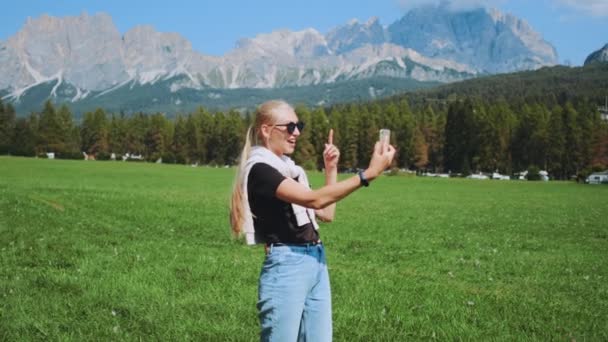Ładna kobieta robi wideo połączenie z pięknego parku przyrody przed górami — Wideo stockowe