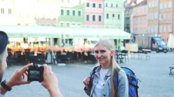 Medium shot of man making photos of female tourist on the view of city market square — Stock Video