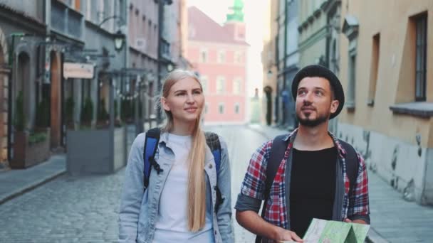 Casal feliz de turistas com mapa andando na rua central da antiga cidade europeia — Vídeo de Stock