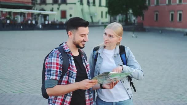 Туристы держат карту и ищут место на городской площади — стоковое видео