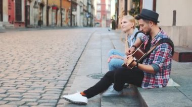 Annem ve annem kaldırımda oturuyor, gitar çalıyor ve dinleniyorlar.