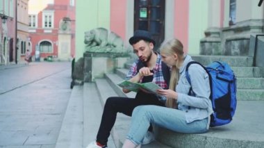 Mutlu turist çift sokak merdivenlerinde oturuyor, şehir haritasını kontrol ediyor ve tartışıyorlar.
