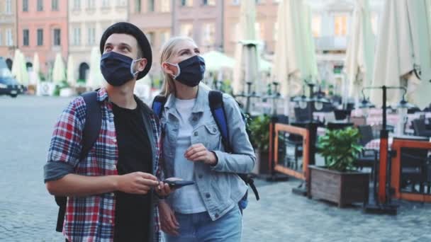 Touristes dans des masques de protection et avec des sacs en utilisant smartphone — Video