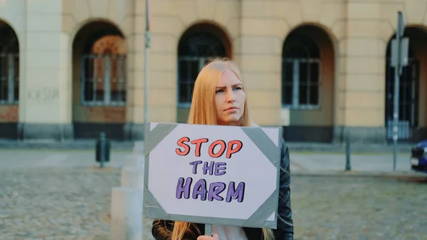 Blonde woman protesting to stop harm by holding steamer