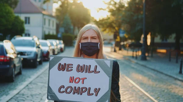 抗议步行：戴着医疗面罩的女人拿着标语牌，上面写着人们不愿服从的话语 — 图库照片
