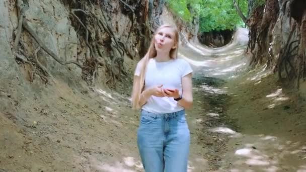 Positive blonde Frau macht Gesichter in natürlicher Lössschlucht — Stockvideo