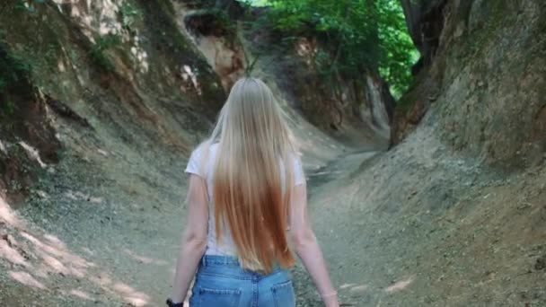 아름다운 금발의 여자가 자연 그대로의 계곡을 걷고 있는 모습 — 비디오
