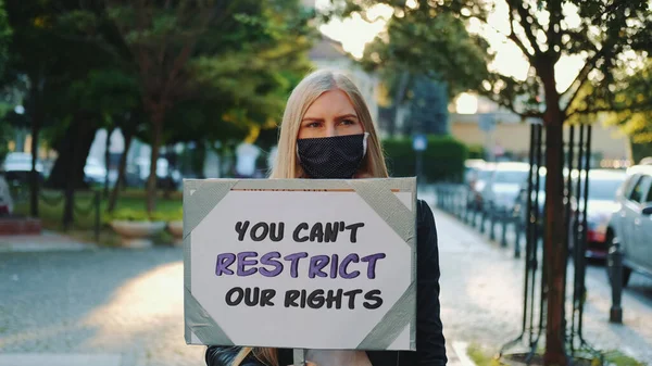 戴着医疗面具抗议人权限制的金发妇女 — 图库照片