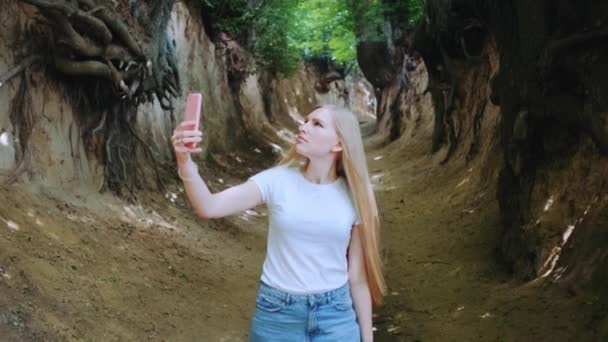 Blondynka młoda kobieta robi zdjęcia na smartfonie w magicznym Roots Gorge — Wideo stockowe