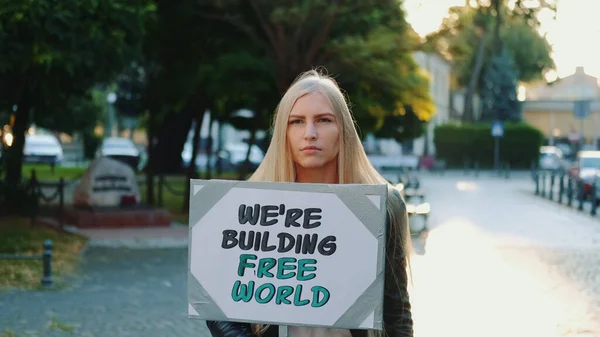 Mulher loira segurando streamer com slogan construindo mundo livre — Fotografia de Stock
