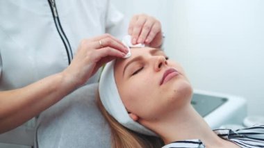 Kozmetik uzmanı, kadınların yüzünü pamukla siliyor.