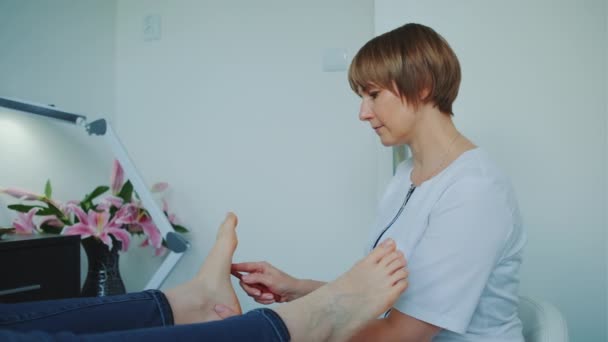 Esteticista haciendo shiatsu masaje de pies usando una varita — Vídeo de stock