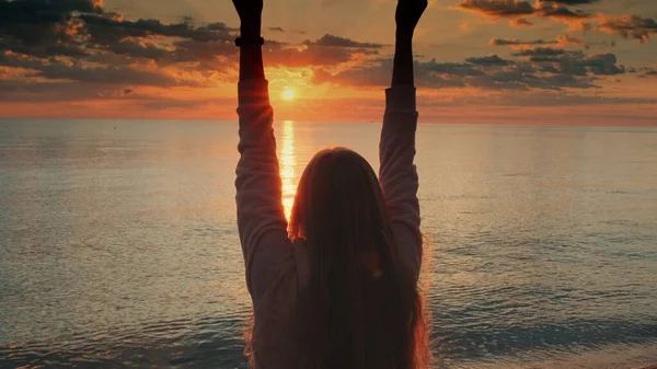 Admirando o nascer do sol na praia mulher levantando as mãos — Fotografia de Stock