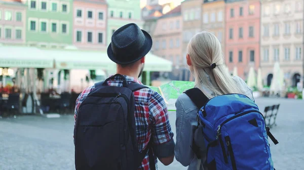 Homem e mulher com sacos verificando mapa na praça central da cidade — Fotografia de Stock