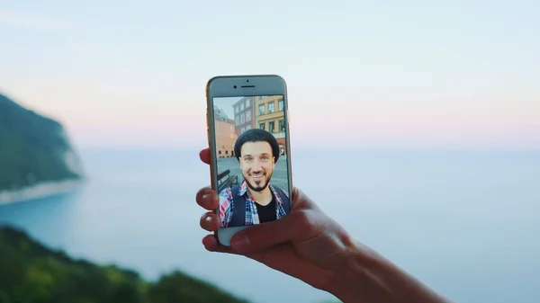 Gros plan du smartphone tenu par la main lors d'un appel vidéo avec un homme devant la mer — Photo