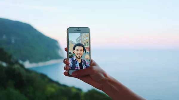 Main tenant smartphone lors d'un appel vidéo avec l'homme devant la mer — Photo