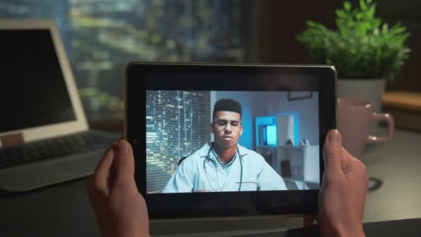Tablet-Bildschirm mit gutaussehendem Arzt, der mit Patient online spricht — Stockvideo