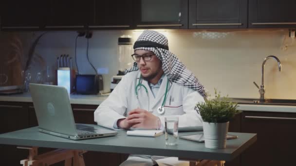 Jovem médico árabe fazendo videoconsulta com paciente em casa à noite — Vídeo de Stock