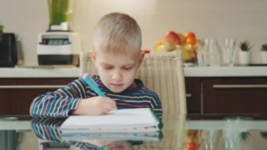 Ödev yazarken kameraya gülümseyen sarışın çocuğun portresi.