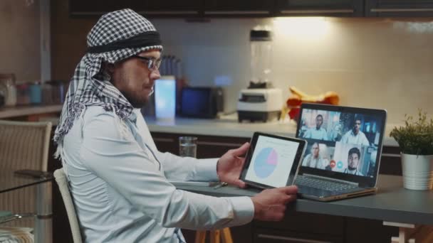 Online meeting on coronavirus infection: arab doctor holding tablet in his hands and comparing data with the report of specialists — Stock Video