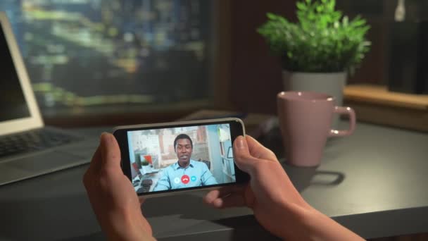 Poziomy ekran smartfona z wideo rozmowy do czarnego biznesmena w biurze — Wideo stockowe
