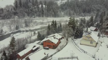 Birds-eye view of private houses at the foot of the mountain by the river in winter