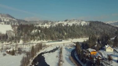 Tren ve küçük dağ yerleşimleriyle güzel kış manzarası.