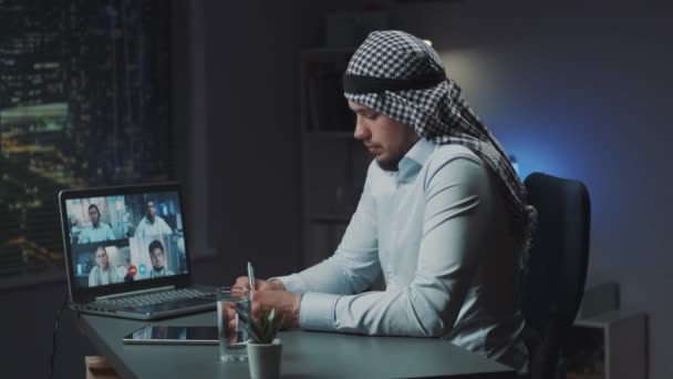 Hombre árabe con kandora sentado en la mesa y videoconferencia con los médicos sobre la enfermedad coronavirus — Vídeo de stock