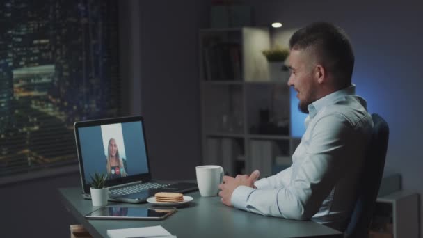 Woman making video call to her friend from vacations while he working in office in the evening — Stock Video