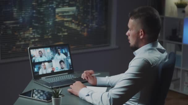 Back view of young businessman having online meeting with multinational team of young leaders — Stock Video