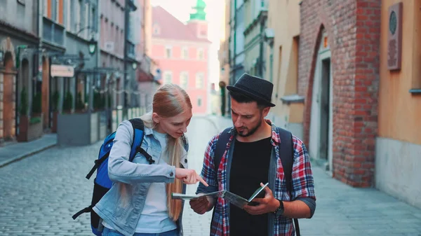 Двоє молодих туристів перевіряють карту під час прогулянки по головній туристичній вулиці Стокова Картинка