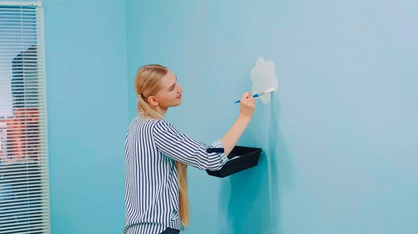 Medium shot of female painting flowers on the wall in office. — Stock Photo, Image