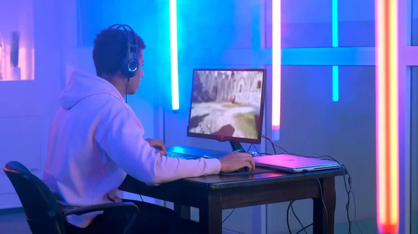 Програвач в навушниках, що грають в онлайн відеогру на персональному комп'ютері Стокове Зображення