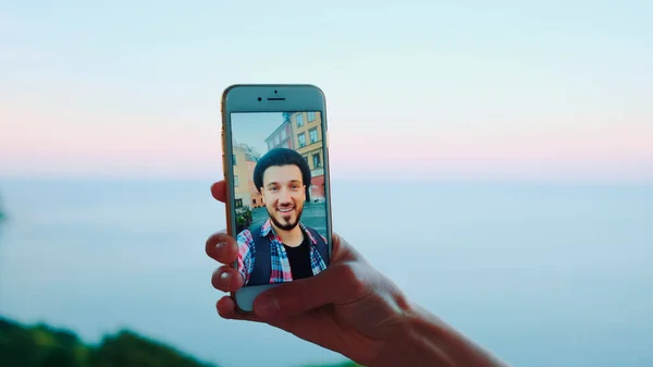 Gros plan du smartphone tenu par la main lors d'un appel vidéo avec un homme devant la mer — Photo