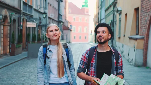 Happy couple of tourists with map walking on central street of old European city — Stock Photo, Image