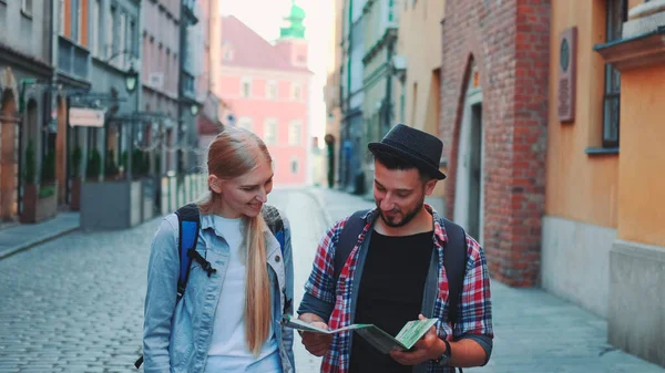 Dos turistas jóvenes revisando el mapa mientras caminan por la calle turística principal Imagen De Stock