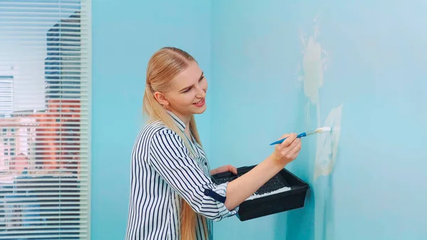 Frau malt Blumen an die Wand. — Stockfoto