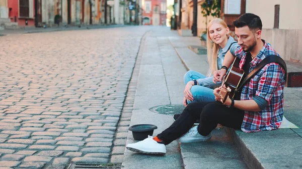 Unga gatusångerskor i gamla stan sitter på trottoaren — Stockfoto