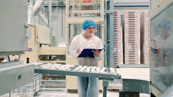 Denetçi, taşıyıcıyı şekerlemelerle kontrol ediyor. Şeker fabrikası.