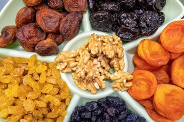 Kurutulmuş meyve ve fındık. Kurutulmuş kayısı, kuru üzüm, kuru erik ve ceviz tabakta yakın plan..